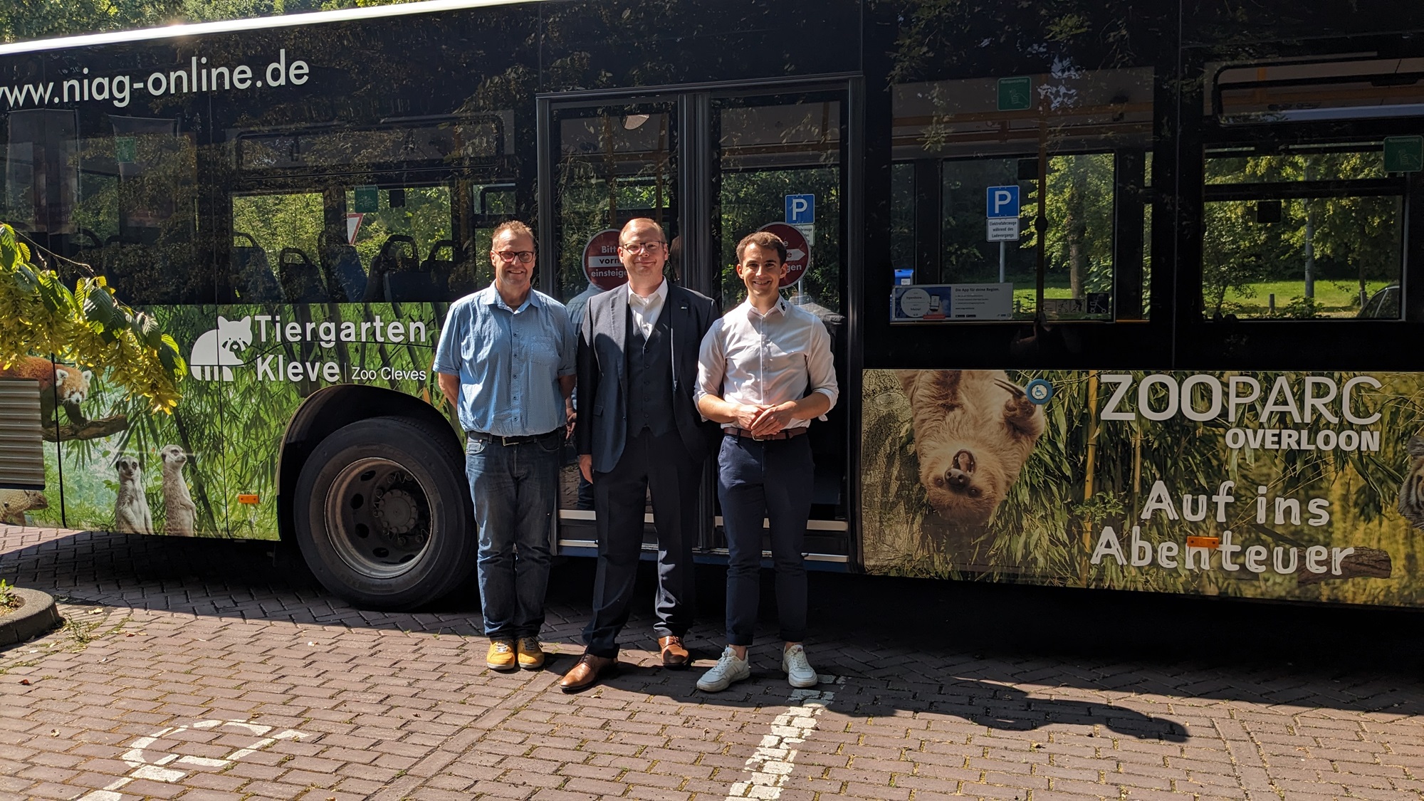 vlnr. Andreas Driessen (RegioStar Media), Tobias Jakubowski (Look Busreisen) und Martin Polotzek (Tiergarten Kleve) vor dem Tiergarten Kleve-ZooParc Overloon-Bus
