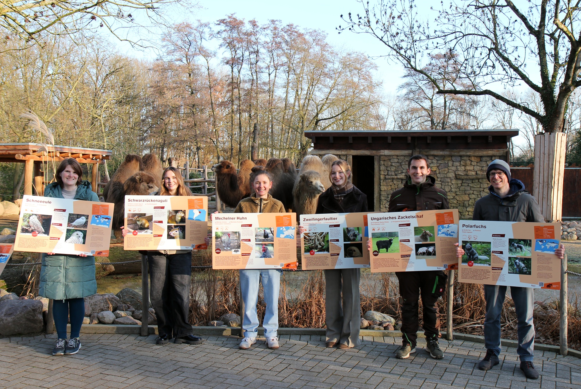 Die Studierende sowie die BetreuerInnen (Ramona Kirsch, li; Axel Huth, re; Martin Polotzek, 2.vr) präsentieren die neuen Tierschilder im Tiergarten Kleve